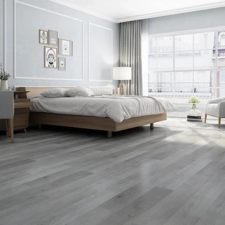 A bedroom with grey wood floors and white walls.